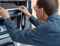 Appliance repair technician replacing a microwave vent filter in Rockford, IL